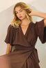 Woman wearing a brown dress against a plain background