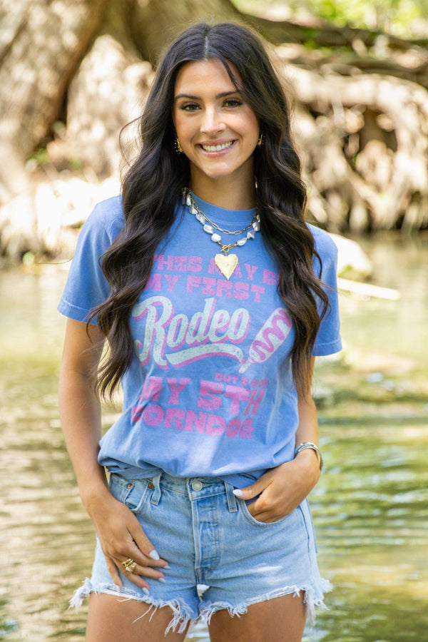 Woman wearing a blue t-shirt with text standing by a body of water.