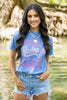 Woman wearing a blue t-shirt with text standing by a body of water.