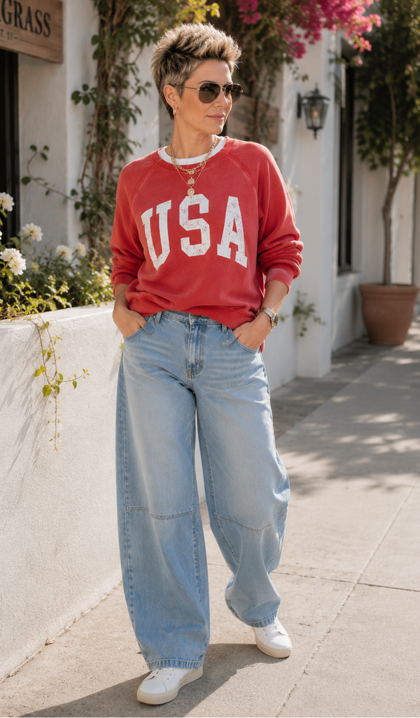 Person wearing a red 'USA' sweatshirt and blue jeans standing outdoors.