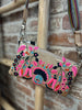 Embroidered clutch bag with floral design on a wooden stand against a brick wall.