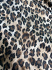 Close-up of leopard print fabric with a greige base and irregular black and brown spots.